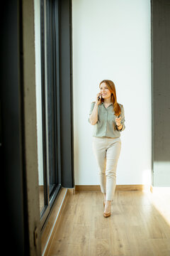 Woman walks and talks on phone in a bright corridor during daytime
