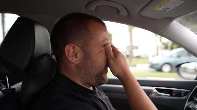 Tired driver rubbing eyes in car fatigue and stress concept