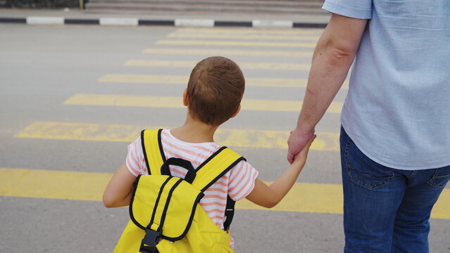 Kid and parent crossing yellow lines, Family values in action, School commute in the city, Child&rsquo;s safety on the road, Urban safety for children, Father and son bonding time, Keeping children safe