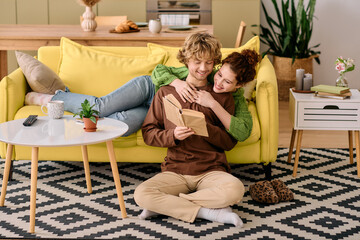 Obraz premium Curly young couple enjoying cozy reading time in their stylish apartment sanctuary