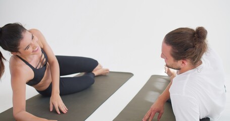 Obraz premium A fit couple playfully interacts during a partner workout on mats, sharing a moment of motivation and fun while exercising together in a bright fitness studio.