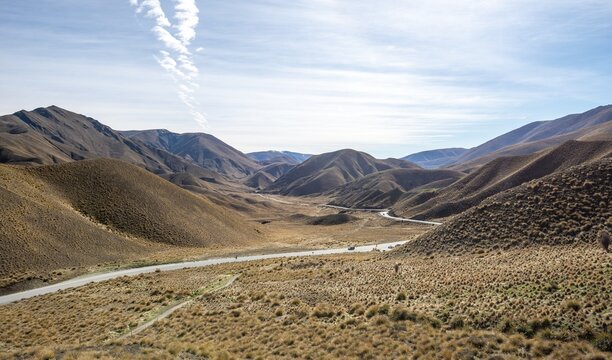 Barren mountain landscape with tufts of grass, pass road, Lindis Pass, Southern Alps, Otago, South Island, New Zealand