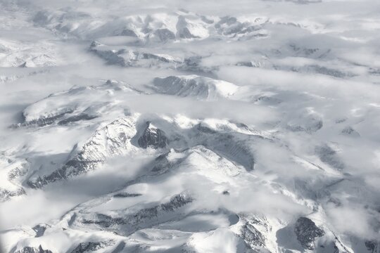 View from the plane to snow-covered mountainous landscape, bird's eye view, Greenland