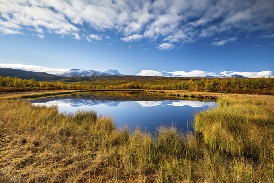 Mountain group Lapporten and snowy mountains of Abisko National Park reflected in small pond, autumnal fell landscape, Abisko, Lapland, Sweden
