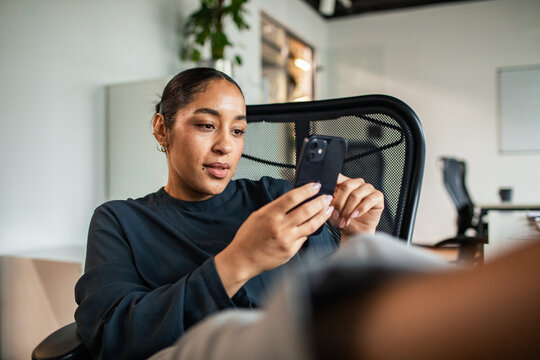 Young woman checking smartphone in modern office