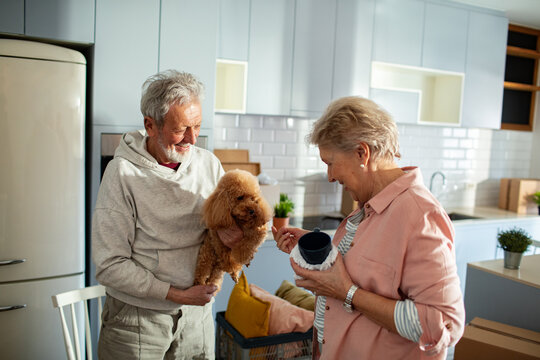 Senior couple with poodle unpacking in a new kitchen
