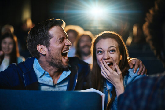 Young couple laughing while watching comedy in cinema