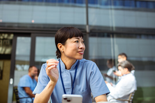 Nurse on break outside hospital with smartphone