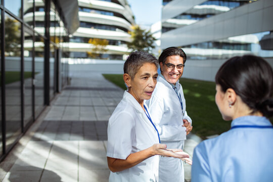 Medical team discussing patient care outside modern hospital