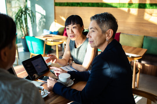 Business colleagues reviewing data on tablet at cafe