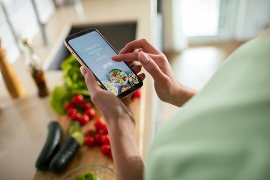 Person using recipe app on smartphone in home kitchen
