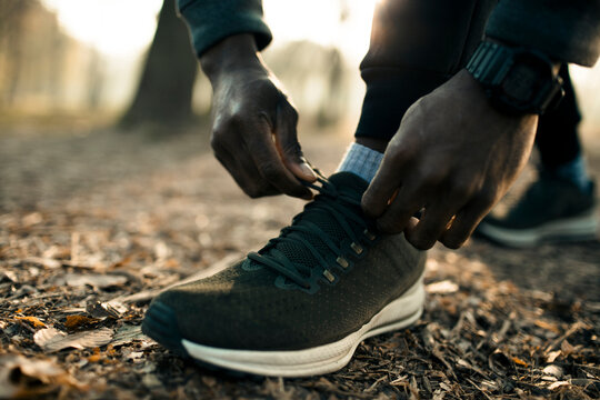 Runner tying shoelaces on forest trail outdoors