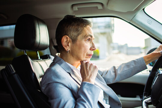 Mature businesswoman driving car in city traffic