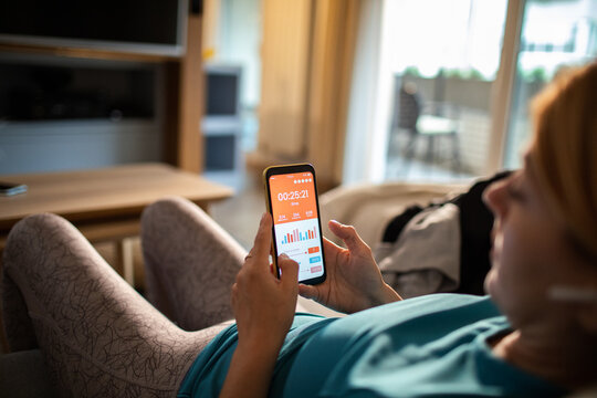 Woman checking fitness app on smartphone at home