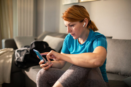 Active woman checking fitness app on phone at home