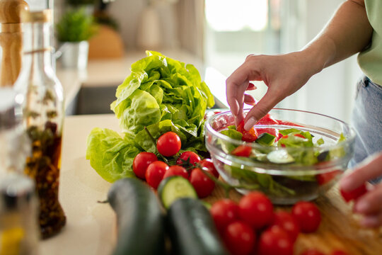 Person preparing fresh vegetable salad at home kitchen