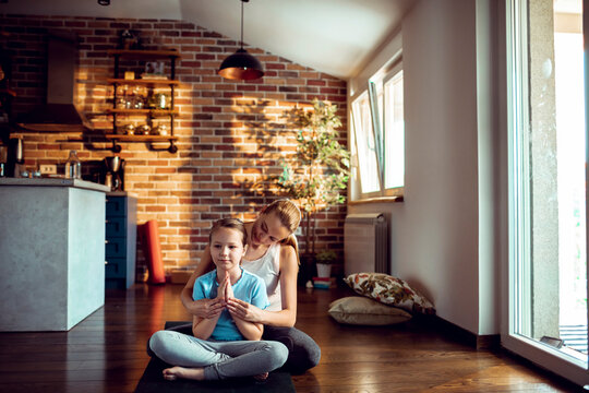 Mother guiding daughter in yoga at home