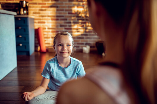 Smiling girl meditating with parent at home