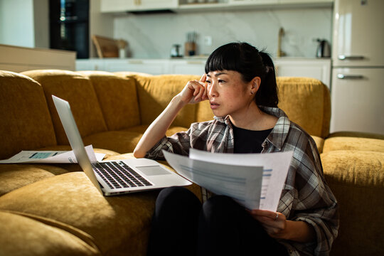 Concerned woman reviewing bills on laptop at home