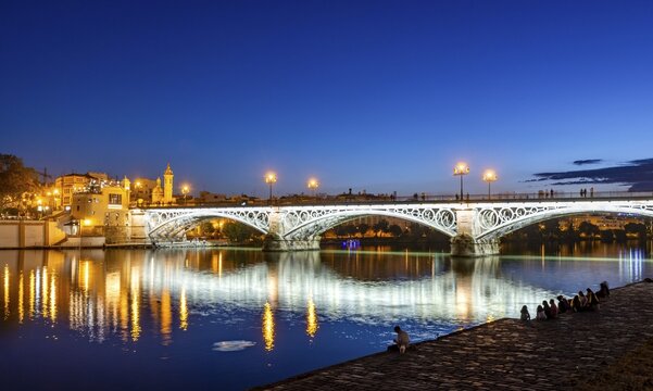 Illuminated bridge Puente de Triana over the river Rio Guadalquivir, blue hour, Sevilla, Andalusia, Spain