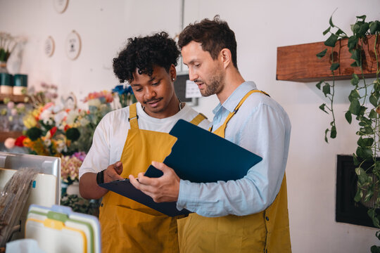 Flower shop employee team reviewing order list in retail store