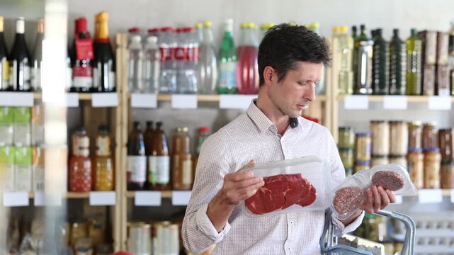 European man holds a package of hamburger meat patties and beef entrecote. Buyer chooses farm meat to cook at home. High quality 4k footage