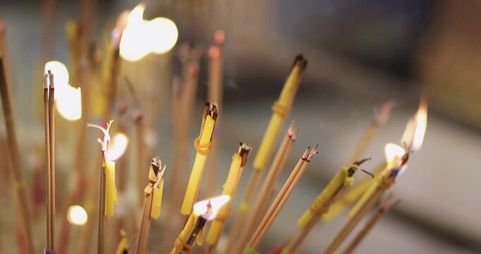 Burning incense sticks and candles in a sacred place symbolizing faith, prayer, spirituality, meditation, devotion, and traditional religious ritual atmosphere in Asian culture, close-up