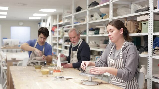 During working day, three pottery workshop workers sculpt from raw clay, form final product. High quality 4k footage