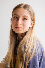 Fototapeta premium Portrait of a 12-year-old blonde pre-teen girl wearing a blue sports t-shirt and blue jeans against a white background