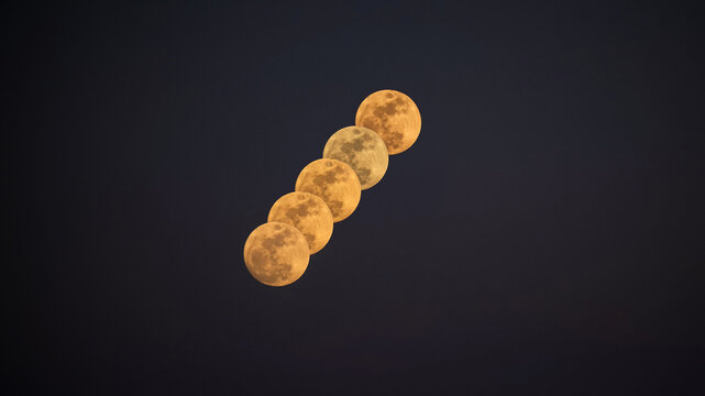 Five full moons appearing in a composite sequence against a dark night sky. Landscape format