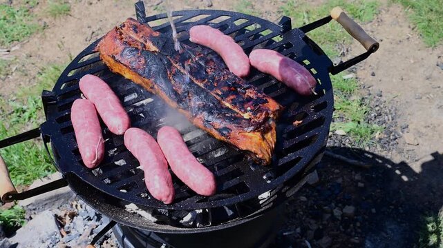 seasoned pork ribs and sausages grilling over an open charcoal fire, featuring a slow zoom-out that captures white smoke billowing from the sizzling meat