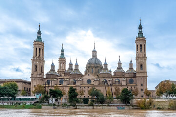 The monumental Basilica of Our Lady of the Pillar stands prominently along the Ebro River in Zaragoza, Spain. Architectural masterpiece features decorative domes. Zaragoza, Spain - November 29, 2021 © ioanna_alexa