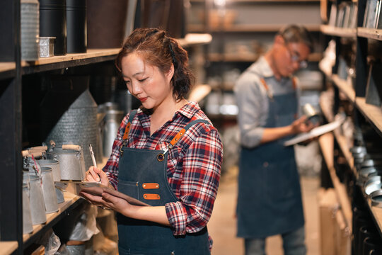 Kitchen staff writing notes in cafe storage aisle