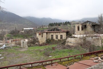 Obraz premium Ruined mountain village with stone houses under a misty sky.