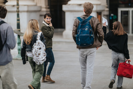 A group of students walking and talking on an urban campus, carrying backpacks and papers. The young people move together outdoors, interacting while heading across a plaza.