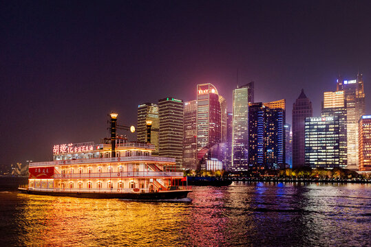 North Bund, Shanghai, China, 04.04.2026 - Illuminated vintage paddlewheel riverboat cruising the Huangpu River at night with glowing Pudong skyline in spring.