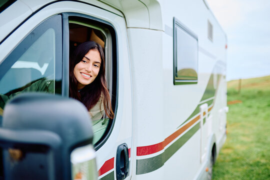 Happy woman enjoying travel and freedom, looking out from her campervan during an outdoor road trip vacation
