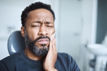 Obraz premium Portrait of a Black man experiencing dental pain, clutching his jaw in a modern clinic