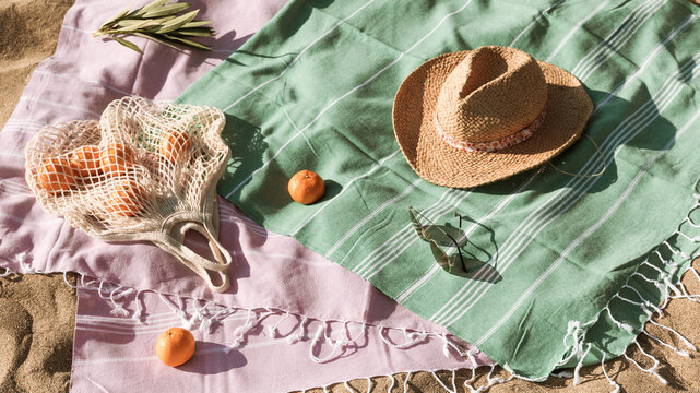 Straw hat, sunglasses, towel, bag on beach sand background. Aesthetic lifestyle, summer vacation concept. Sunbathing, beach party set, holiday picnic. Travel fashionable blog, social media, top view.