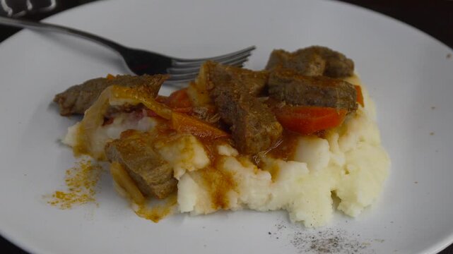 Beef goulash potatoes served on a white plate with tender meat chunks and carrots for a hearty homemade dinner meal