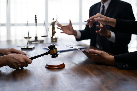 Lawyers discussing case with judge holding gavel in courtroom