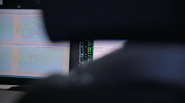 Person Analyzing Data on Multiple Computer Monitors in Office Setting