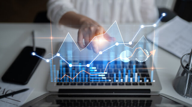 Professional individual engages with digital analytics and data visualizations on a laptop in a modern office, showcasing technology for informed decision-making. Scalp
