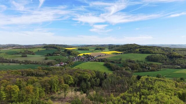 Expansive view over a rural landscape with rolling hills, forests, and a small german village