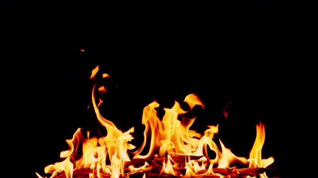 Slow motion flames dancing against a deep black background, creating a dramatic and powerful fire effect. Abstract burning fire with glowing orange and yellow tongues of flame, ideal for backgrounds, 