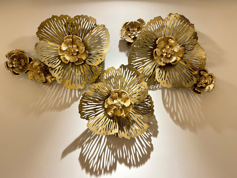 Close up of wrought iron sculpture, gold metal flower art as wall decoration or accessories. Antique iron crafts with layered petals and intricate details for modern interior decoration.