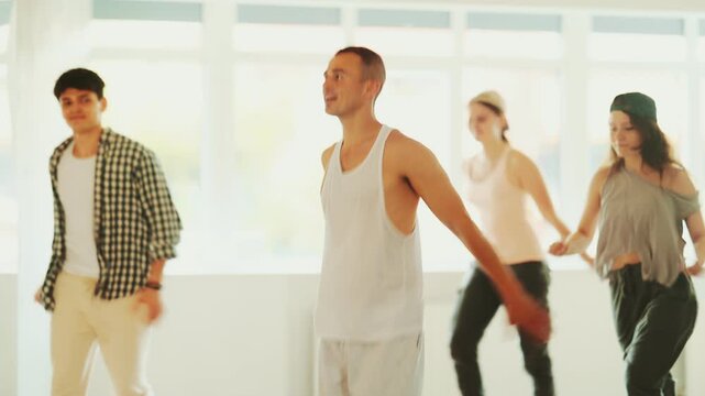 Active young guys and girls practicing hip-hop reject step in training hall during dancing classes. High quality 4k footage