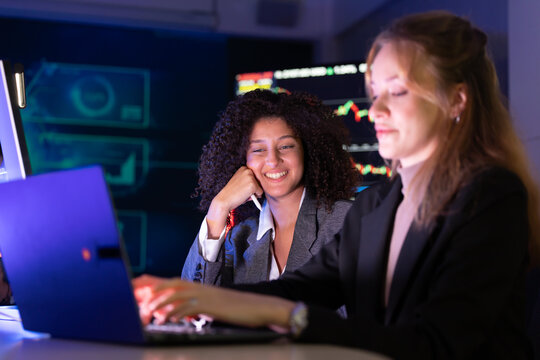 Colleagues discuss stock market trends in a modern office setting during evening hours