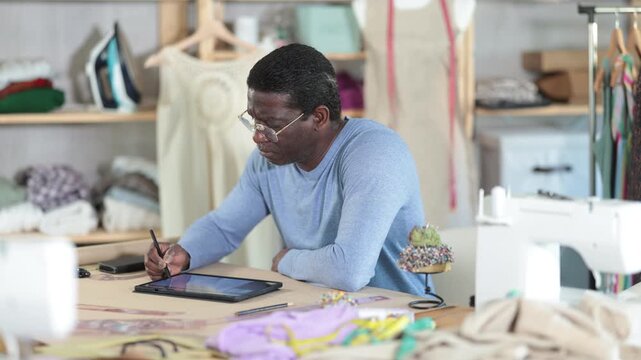 Male dressmaker working on digital sketch of dress in workshop