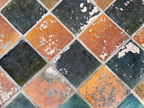 Close up of weathered porcelain brown and black floor tiles with grunge and dirt texture. Decayed and weathered diamond tiles. Ancient and aged ruins. Seamless background texture.